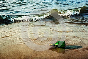 Message bottle on beach in waves