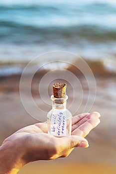 Message in a bottle with inscription: we will definitely return. Concept with copy space