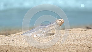 Message in a bottle on the tropical beach of exotic island, turquoise waves of the sea in background