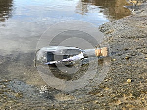 Message in a crystal bottle in the beach with water and sand