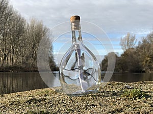 Message in a crystal bottle in the beach with water and sand