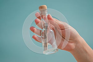 Message in a glass bottle in a woman`s hand. Sea and blue sky. Found a note on salvation, please help