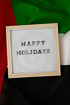 Message HAPPY HOLIDAYS on background waving flag of UAE. Independence Commemoration Day Muslim, Ramadan, Day of flag