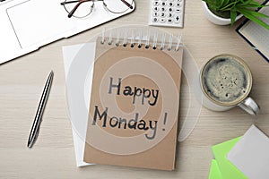 Message Happy Monday written in notebook, office stationery and cup of coffee on wooden  desk, flat lay