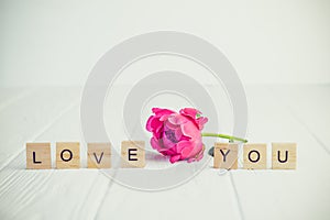 Message I love you spelled in wooden blocks with pink peony bud flower on white wooden table. Love, Valentines day background. Gif