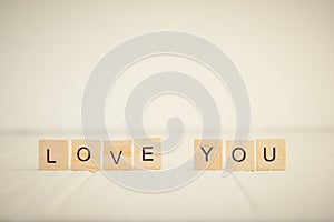 Message I love you spelled in wooden blocks standing on white wooden table. Valentines day background. Simplicity concept. Vintage