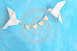 Message of love and kindness. Two white dove origami carrying heart shape on blue background.