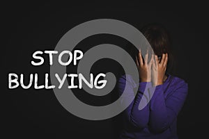 Message STOP BULLYING and abused girl crying near black wall