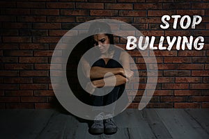 Message STOP BULLYING and abused teen girl crying near wall