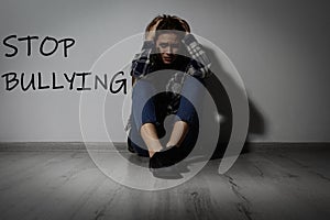 Message STOP BULLYING and abused teen girl crying near wall