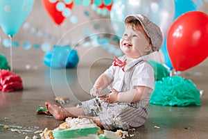 Messy baby boy eating cake on his 1st birthday looking up