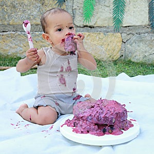 Messy baby boy eating first birthday cake