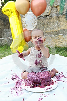 Messy baby boy eating first birthday cake