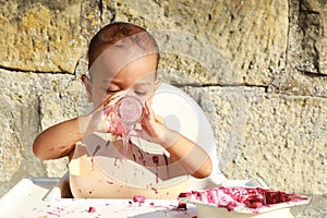 Messy baby boy poring water from glass