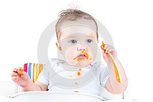 Messy baby eating her first solid vegetable food