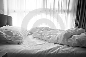 Messy bed. White pillow with blanket on bed unmade.