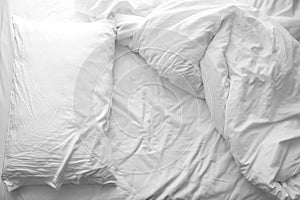 Messy bed. White pillow with blanket on bed unmade.