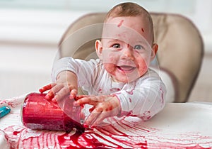 Messy and dirty baby is eating snack with hands photo