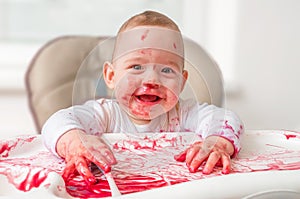 Messy and dirty baby is eating snack with hands photo