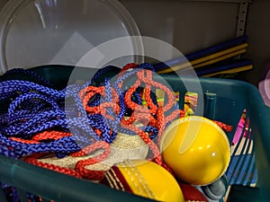 A messy disorganised basket of coloured cord rope in a school games storage cupboard