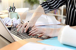 Messy entrepreneur hands working on laptop on a desk