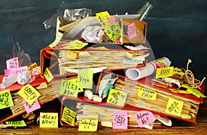 Messy file folder,sticky notes and old papers on a cluttered , chaotic office desk. Red tape, bureaucracy,overworked,burnout,