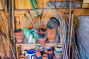 Messy gardening tools in tool shed stacked on shelf