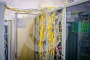 Messy internet wires have a connection to computer servers. Cabinets with computer equipment are located in the data center. Racks