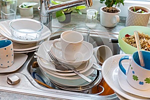 Messy kitchen counter with pile of dirty dishes in sink - Compulsive Hoarding Syndrome