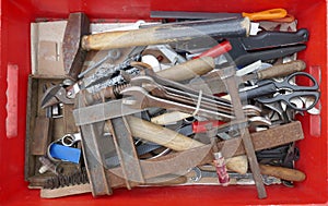 Messy old rusty hand tools in a red plastic box