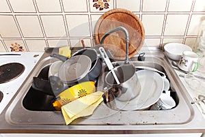 Messy sink in domestic kitchen with dirty crockery