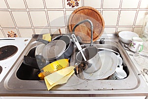 Messy sink in domestic kitchen with dirty crockery photo
