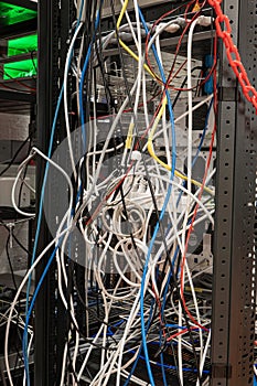 Messy tangled electric cables connecting to industrial lab devices on a rack, no people