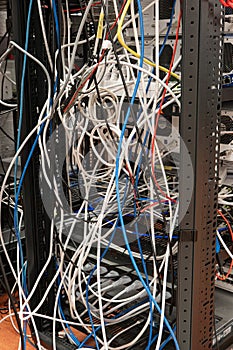 Messy tangled electric cables connecting to industrial lab devices on a rack, no people