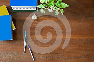 Messy textbooks, notebooks, documents,pens,green plant,pocket watch and hot white coffee cup on vintage grunge wooden background