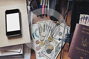 Messy working table, with cash, passport, smartphone, laptop, and etc.