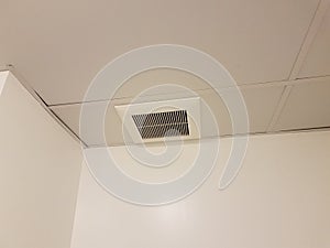 Metal air vent or register on the ceiling with white walls