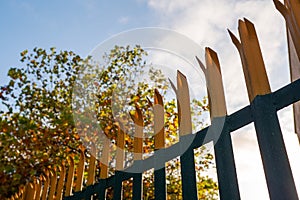 Metal anti climbing fence with spikes on top. Secure perimeter of property. Blue cloudy sky