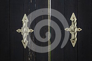 Metal antique handles on black wooden gates. Close-up