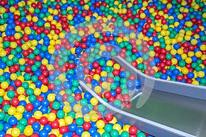 Metal baby slide going down to the pool with many colored balls in the kids playing room