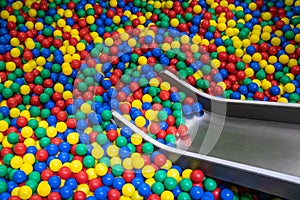 Metal baby slide going down to the pool with many colored balls in the kids playing room