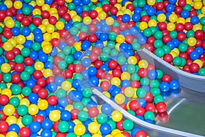 Metal baby slide going down to the pool with many colored balls in the kids playing room