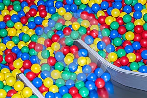 Metal baby slide going down to the pool with many colored balls in the kids playing room