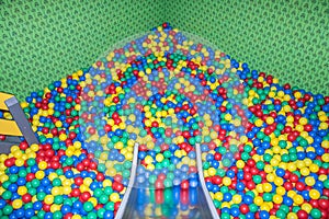 Metal baby slide going down to the pool with many colored balls in the kids playing room