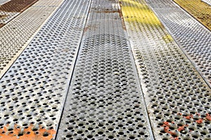 Metal background with perforation of square holes. Gray and colorful steel texture of sand metal sheet