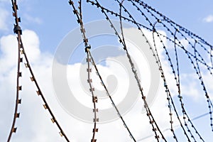 Barbed wire against blue sky with clouds