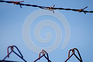 metal barbed wire on a background of clear blue sky, close-up. detail of barbed wire fence