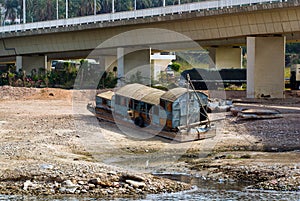 Metal barge of the Nile river in Egypt, stranded on the river bank under a bridge a