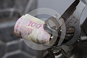 Metal barrel and Ukrainian money, the concept of the cost of gasoline, diesel, gas. Refilling the car. Roll of banknotes 100