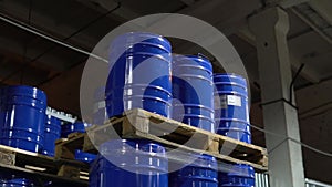 Metal barrels row stacked inside stock warehouse. Blue hogsheads stack piled on pallets in a large industrial supply storage